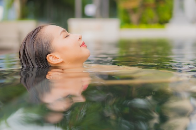 Gratis foto ontspant de portret mooie jonge aziatische vrouw glimlach rond openluchtzwembad in hoteltoevlucht op vakantiereizen