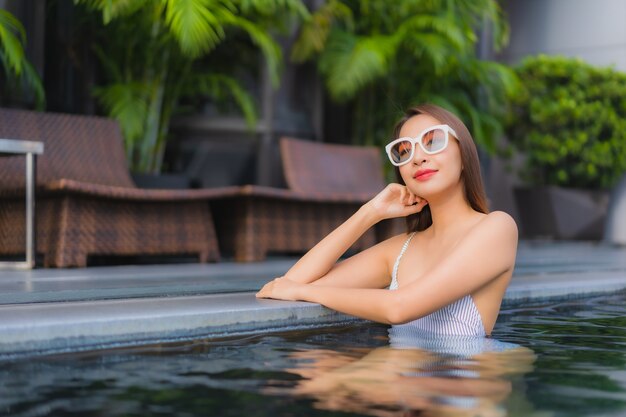Ontspant de portret mooie jonge aziatische vrouw glimlachvrije tijd rond openluchtzwembad