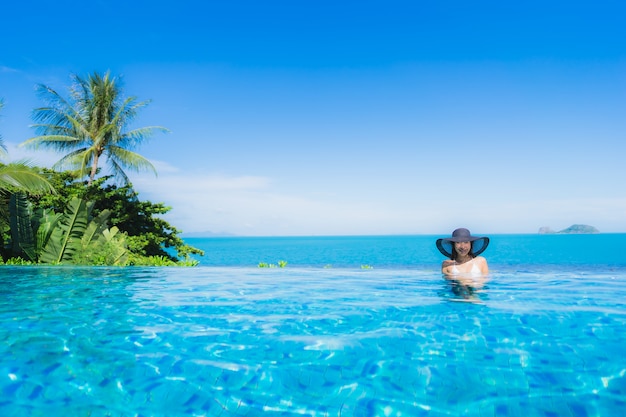 Ontspant de portret mooie jonge Aziatische vrouw in luxe openlucht zwembad in bijna het strand overzeese van de hoteltoevlucht oceaan