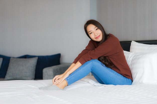 Ontspant de portret mooie jonge Aziatische vrouw op bed in slaapkamerbinnenland