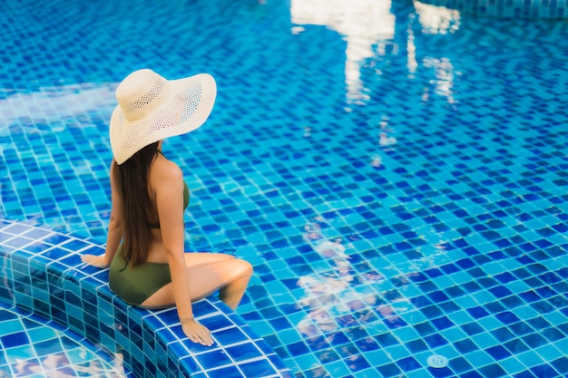Ontspant de portret mooie jonge Aziatische vrouw rond zwembad in hoteltoevlucht