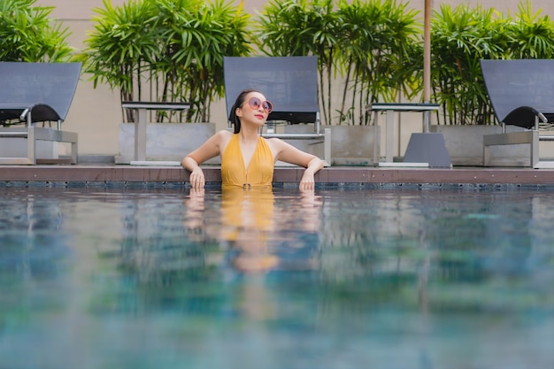 Ontspant de portret mooie jonge Aziatische vrouw vrije tijd rond zwembad
