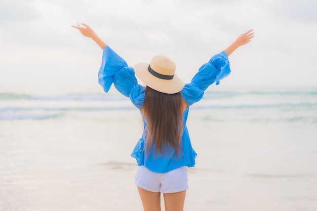 Ontspant de portret mooie jonge Aziatische vrouw vrijetijdsglimlach rond strand overzeese oceaan in zonsondergangtijd