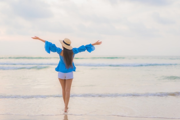 Ontspant de portret mooie jonge aziatische vrouw vrijetijdsglimlach rond strand overzeese oceaan in zonsondergangtijd