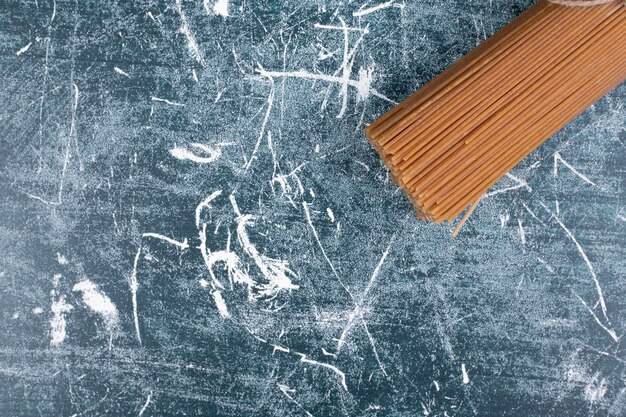 Onvoorbereide deegwarenbos van volkoren spaghetti vastgebonden met touw op marmeren backgroundto