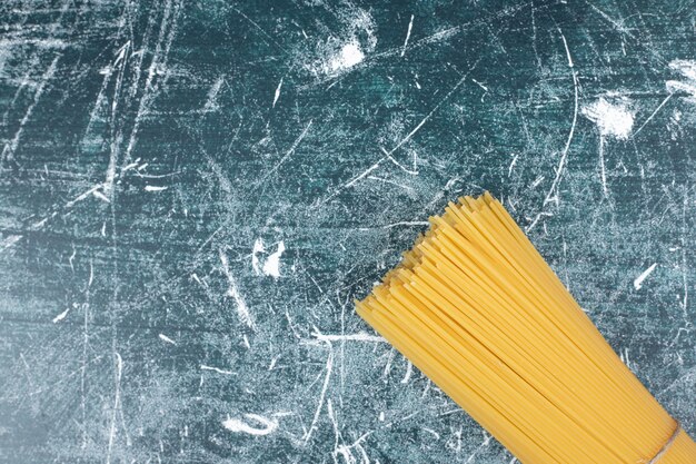 Onvoorbereide deegwarenbos van volkoren spaghetti vastgebonden met touw op marmeren backgroundto