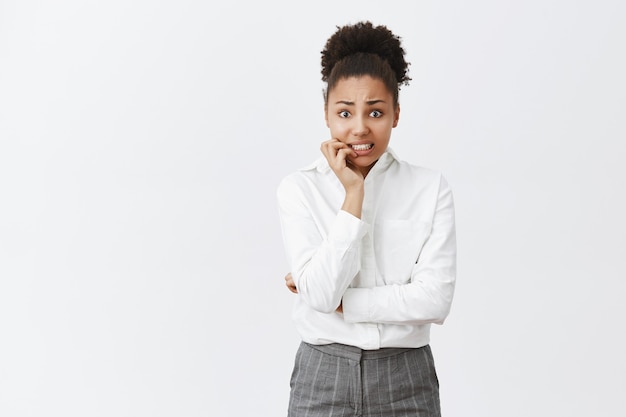 Onzekere bezorgde Afro-Amerikaanse vrouw die nagels bijt, heeft grote problemen