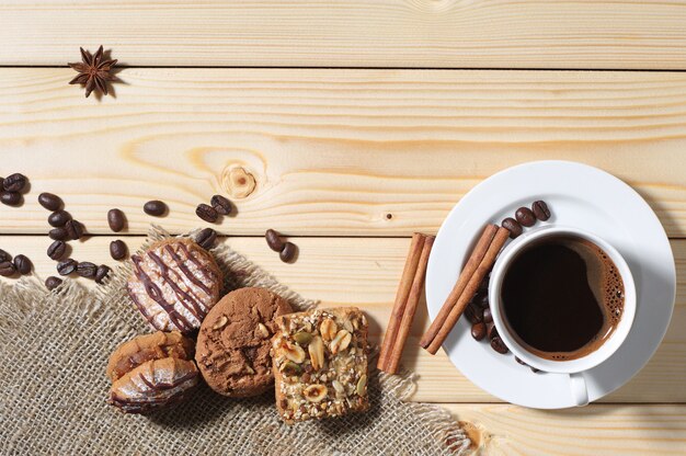 Op een houten tafel staan verschillende koekjes, een kop warme koffie en ruimte voor uw tekst. bovenaanzicht