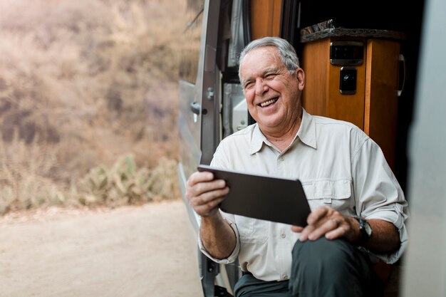 Opa zit in camper terwijl hij naar zijn tablet kijkt