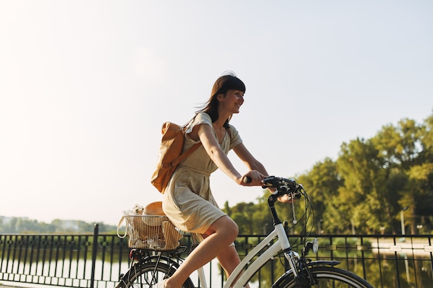 Openluchtportret van aantrekkelijk jong brunette in een hoed op een fiets.