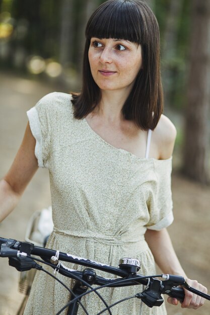 Openluchtportret van aantrekkelijk jong brunette op een fiets.