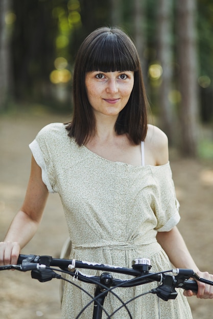 Openluchtportret van aantrekkelijk jong brunette op een fiets.