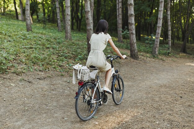 Openluchtportret van aantrekkelijk jong brunette op een fiets.