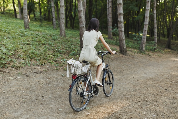 Openluchtportret van aantrekkelijk jong brunette op een fiets.
