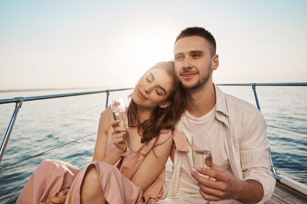 Openluchtportret van volwassen gelukkig mannetje en wijfje in liefde, die hun verloving op jacht vieren, glas champagne houden en koesteren. Vriend vertelde zojuist over dingen die hij leuk vindt in haar