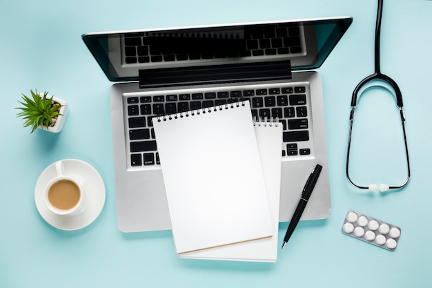Opgeheven mening van blocnote op laptop dichtbij koffiekop en succulente installatie over medisch bureau