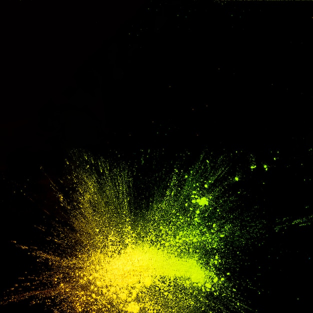 Opgeheven mening van de explosie van het gele kleurenpoeder op zwarte achtergrond