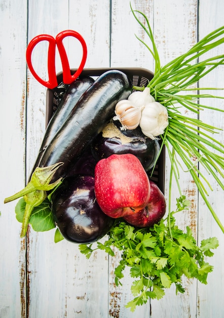 Opgeheven mening van een landbouwbedrijf verse groenten en fruit in mand over houten lijst