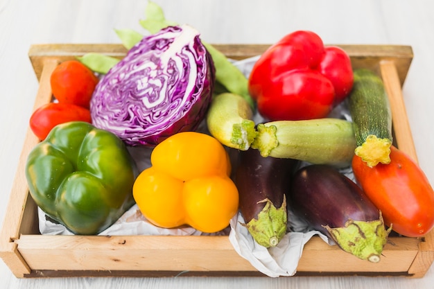 Opgeheven mening van kleurrijke groenten in houten container