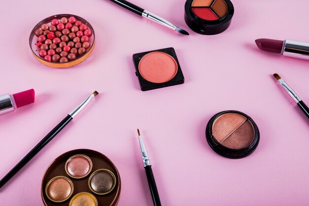 Opgeheven mening van make-upuitrusting met borstels op roze achtergrond
