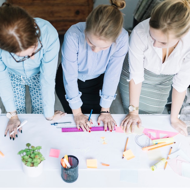 Gratis foto opgeheven mening van onderneemsters die de bedrijfsgrafiek op papier over bureau plannen