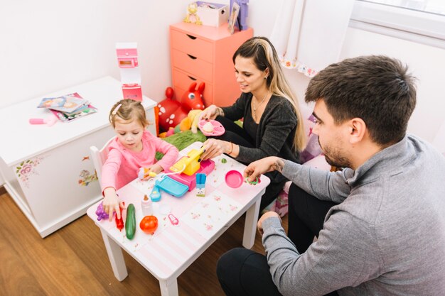 Opgeheven mening van ouders die hun dochter bekijken die met speelgoed spelen