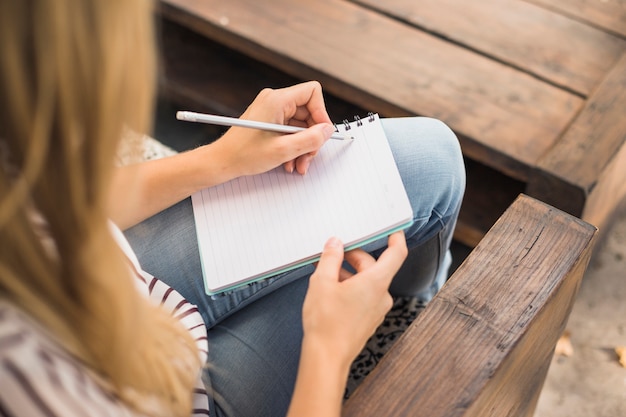 Opgeheven mening van vrouw die op notitieboekje schrijft