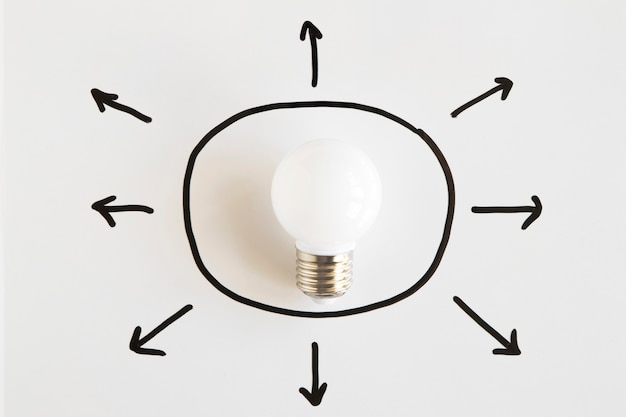 Opgeheven mening van witte die gloeilamp met pijlsymbolen wordt omringd die diverse richtingen tonen