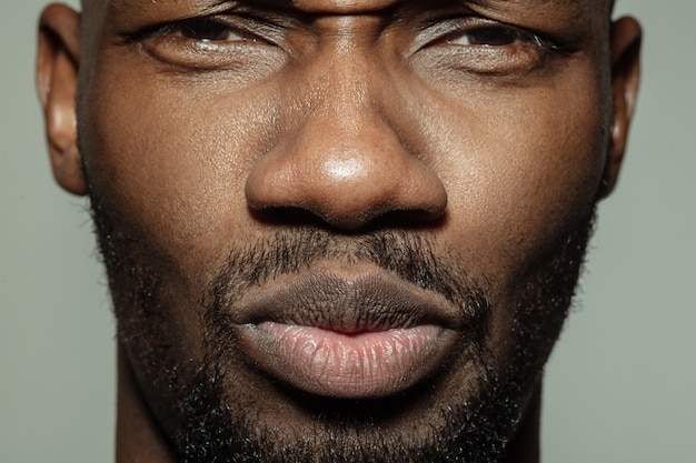 Opgelucht, kalm. Close up van gezicht van mooie Afro-Amerikaanse jongeman, focus op mond.