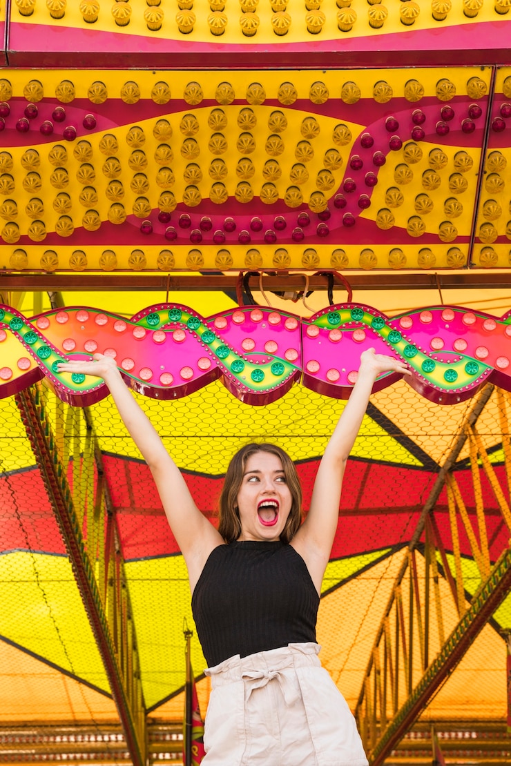 Gratis Foto opgewekte jonge vrouw die bij pretpark geniet van