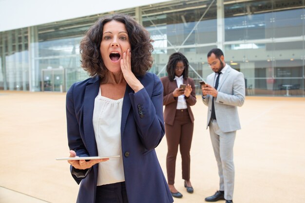 Opgewekte onderneemster met tablet die groot schokkend nieuws krijgen