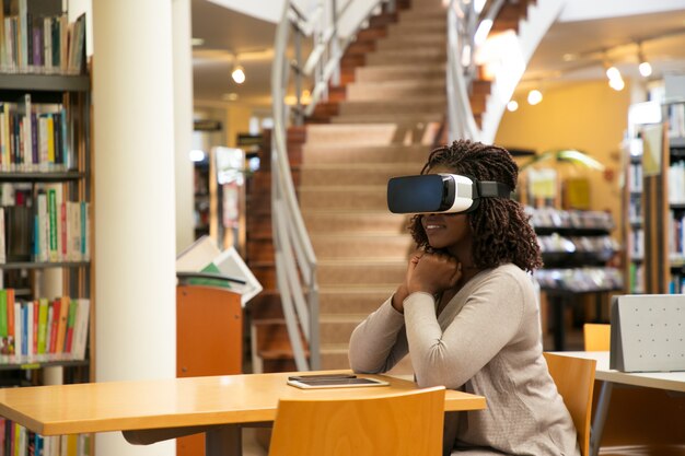 Opgewekte vrouwelijke student die virtuele video bekijkt