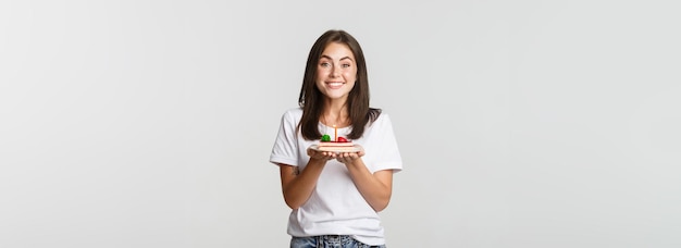 Opgewonden aantrekkelijke brunette verjaardag meisje wens op verjaardagstaart witte achtergrond