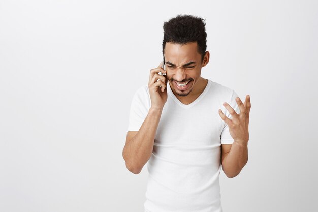 Opgewonden gelukkig Afro-Amerikaanse man praten over de telefoon en vrolijk glimlachen