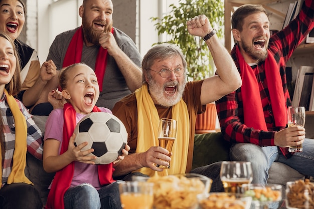 Opgewonden, gelukkige grote familie voetbal kijken, voetbalwedstrijd op de bank thuis.