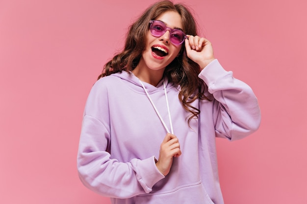 Opgewonden gelukkige vrouw in paarse hoodie lacht breed
