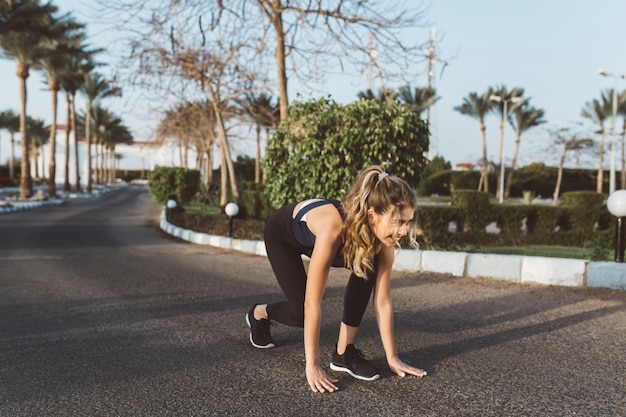 Opgewonden gemotiveerde geweldige vrouw die zich voorbereidt om in zonnige ochtend op straat te rennen. Training, training, positiviteit uiten, ware emoties, gezonde levensstijl, hardwerkend