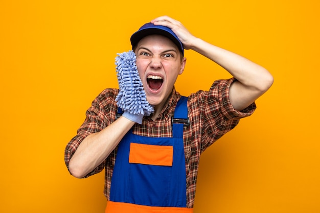 Opgewonden greep het hoofd van een jonge schoonmaakster die een uniform draagt en een pet met een vod op het gezicht