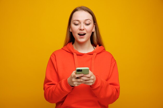 Opgewonden jonge blonde vrouw met behulp van mobiele telefoon