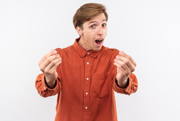 Opgewonden jonge knappe man met een rood shirt met een tipgebaar dat op een witte muur wordt geïsoleerd