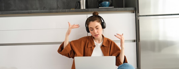 Gratis foto opgewonden jonge vrouwelijke programmeur bereikt doel triomferend winnen op laptop zitten in koptelefoon