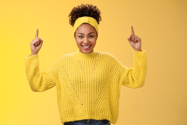 Opgewonden schattig vrouwelijk afro-amerikaans jong meisje afro kapsel in hoofdband trui wijzende vinger...