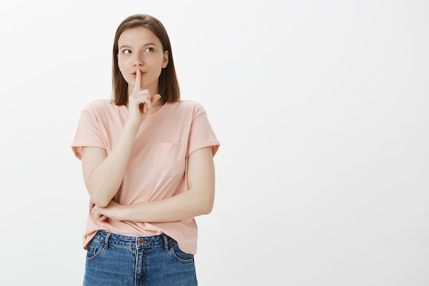 Opgewonden schattige vrouw heeft een geheim, shhh-gebaar, bereid verrassing voor, zwijgzaam, vraag zwijg