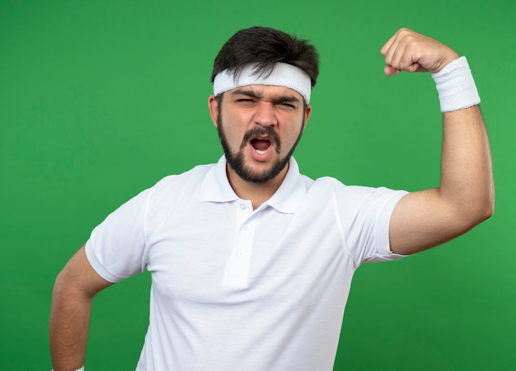 Gratis Foto opgewonden sportieve jongeman met hoofdband en polsbandje met sterk gebaar