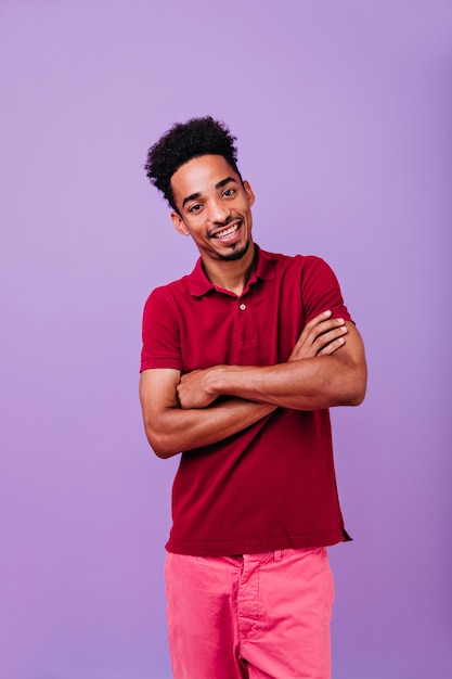 Opgewonden stijlvolle jongen poseren met gekruiste armen. Indoor foto van enthousiaste mannelijke model staan.