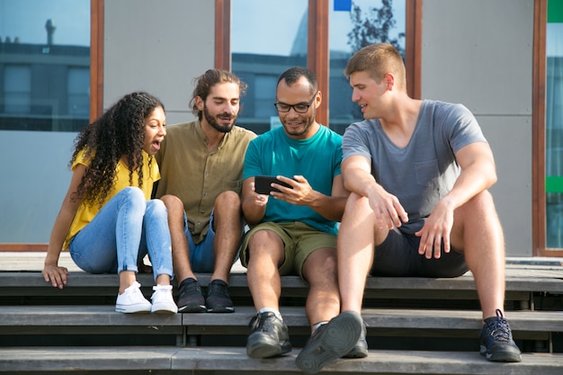 Opgewonden vrienden kijken naar video op mobiele telefoon