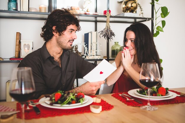 Opgewonden vriendin terwijl haar vriendje leest een romantische postkaart