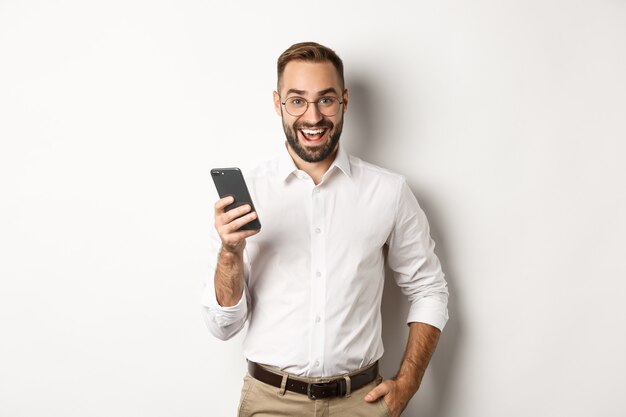 Opgewonden zaken man met behulp van mobiele telefoon, verbaasd kijken, staan.