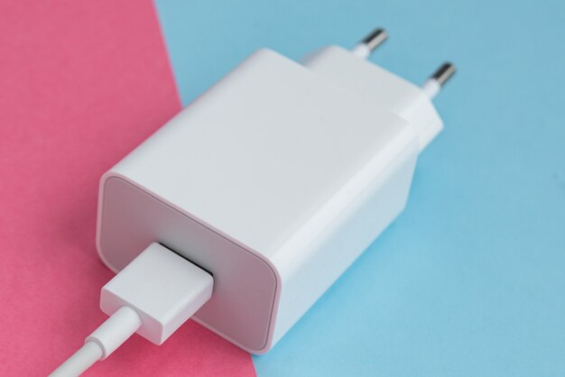 Oplader en USB-kabel type C over roze en blauwe achtergrond