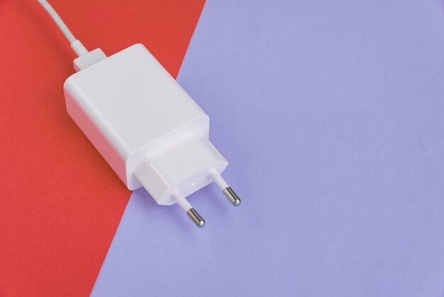 Oplader en USB-kabel type C over roze en blauwe achtergrond